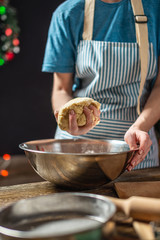 Young woman housewife makes dough for cooking holiday ginger cookies. Home atmosphere in the evening on Christmas eve