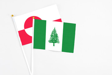 Norfolk Island and Greenland stick flags on white background. High quality fabric, miniature national flag. Peaceful global concept.White floor for copy space.
