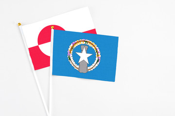 Northern Mariana Islands and Greenland stick flags on white background. High quality fabric, miniature national flag. Peaceful global concept.White floor for copy space.