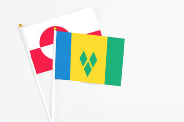 Saint Vincent And The Grenadines and Greenland stick flags on white background. High quality fabric, miniature national flag. Peaceful global concept.White floor for copy space.