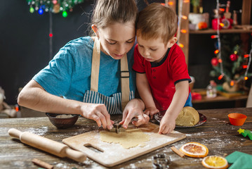 Fototapeta na wymiar Mom and child son shape the dough for baking homemade holiday gingerbread. Family cooking in Christmas decorations