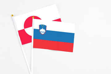 Slovenia and Greenland stick flags on white background. High quality fabric, miniature national flag. Peaceful global concept.White floor for copy space.