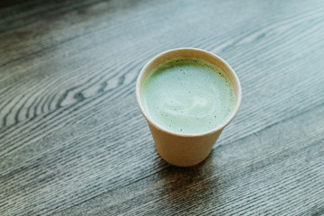 The girl holds in his hand a paper cup of tea macha. Classic powdered japanese traditional green tea. Fresh hot morning drink. Breakfast mood. Woman relax in tea time. Healthy lifestyle