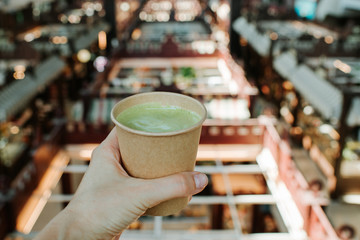 The girl holds in his hand a paper cup of tea macha. Classic powdered japanese traditional green tea. Fresh hot morning drink. Breakfast mood. Woman relax in tea time. Healthy lifestyle