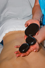 Wellness concept. Handsome young man relaxing under the stimulating effect of a traditional hot stone massage in a luxury spa and wellness center. Recovery after work.
