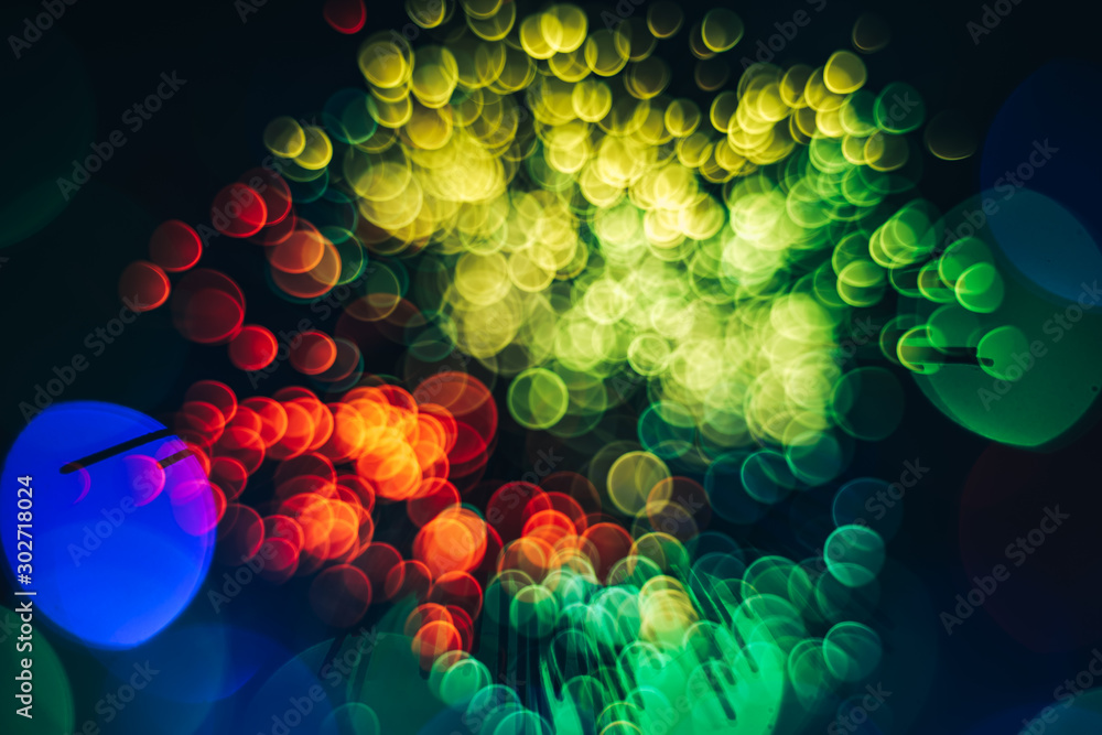 Poster beautiful multi colored abstract optical light bokeh on a dark background.