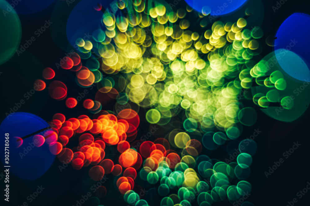 Poster beautiful multi colored abstract optical light bokeh on a dark background.