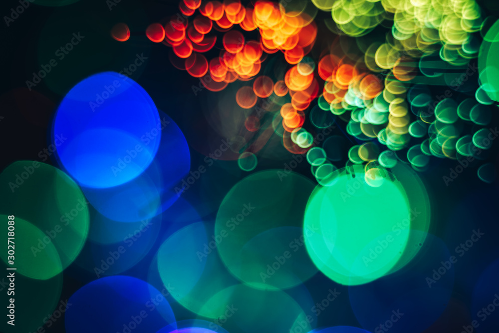 Poster beautiful multi colored abstract optical light bokeh on a dark background.
