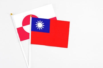 Taiwan and Greenland stick flags on white background. High quality fabric, miniature national flag. Peaceful global concept.White floor for copy space.