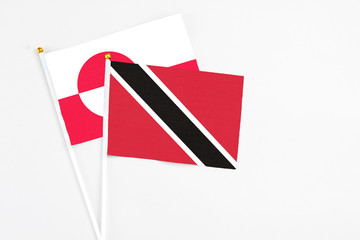 Trinidad And Tobago and Greenland stick flags on white background. High quality fabric, miniature national flag. Peaceful global concept.White floor for copy space.