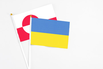 Ukraine and Greenland stick flags on white background. High quality fabric, miniature national flag. Peaceful global concept.White floor for copy space.