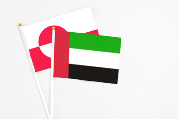 United Arab Emirates and Greenland stick flags on white background. High quality fabric, miniature national flag. Peaceful global concept.White floor for copy space.
