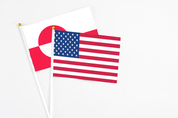 United States and Greenland stick flags on white background. High quality fabric, miniature national flag. Peaceful global concept.White floor for copy space.