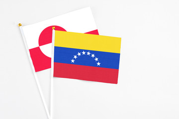 Venezuela and Greenland stick flags on white background. High quality fabric, miniature national flag. Peaceful global concept.White floor for copy space.