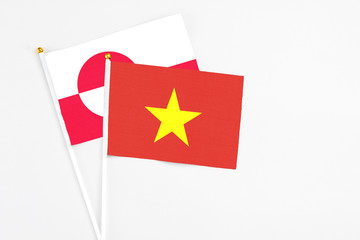 Vietnam and Greenland stick flags on white background. High quality fabric, miniature national flag. Peaceful global concept.White floor for copy space.
