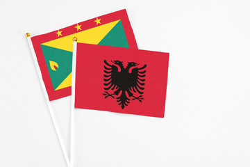 Fototapeta premium Albania and Grenada stick flags on white background. High quality fabric, miniature national flag. Peaceful global concept.White floor for copy space.