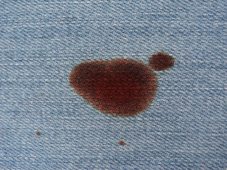 Stain of blood or wine on textile. Denim texture. 