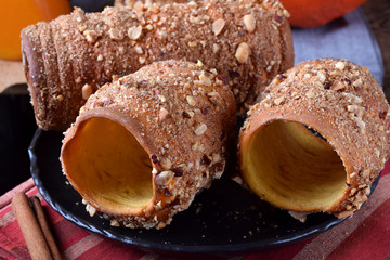 Trdelnik covered in nuts and sugar on the black plate. Czech street food