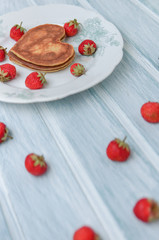 Pancakes and strawberry on a light blue white background. Heart shaped pancakes for boy friend