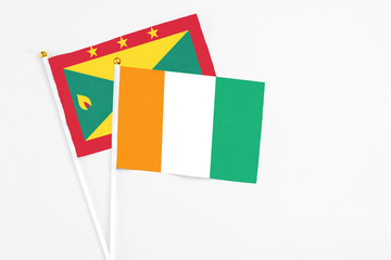 Cote D'Ivoire and Grenada stick flags on white background. High quality fabric, miniature national flag. Peaceful global concept.White floor for copy space.