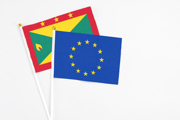 European Union and Grenada stick flags on white background. High quality fabric, miniature national flag. Peaceful global concept.White floor for copy space.