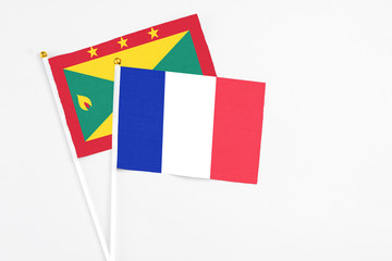 France and Grenada stick flags on white background. High quality fabric, miniature national flag. Peaceful global concept.White floor for copy space.