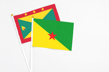 French Guiana and Grenada stick flags on white background. High quality fabric, miniature national flag. Peaceful global concept.White floor for copy space.
