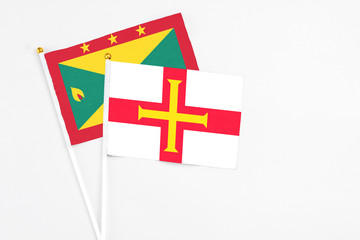 Guernsey and Grenada stick flags on white background. High quality fabric, miniature national flag. Peaceful global concept.White floor for copy space.