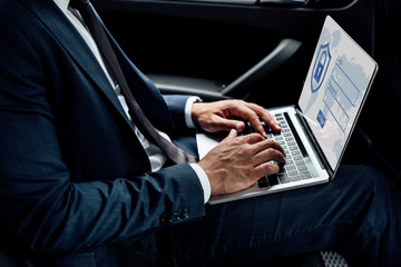 partial view of african american businessman using laptop with internet security illustration in car