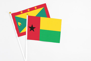 Guinea Bissau and Grenada stick flags on white background. High quality fabric, miniature national flag. Peaceful global concept.White floor for copy space.