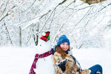 young beautiful woman playing with snowman