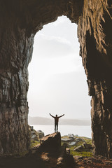 Man standing alone in cave Travel adventure vacations happy raised hands tourist success wellness...