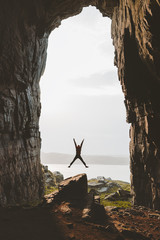 Man jumping in cave Travel adventure vacations happy emotions success achievement concept Kirkehelleren grotto in Norway