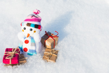 toy snowman with gifts in the snow
