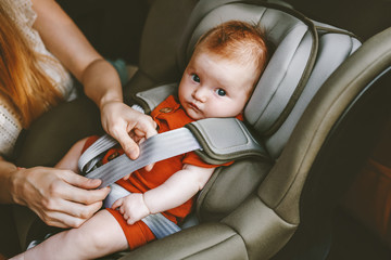 Child in car mother putting baby in safety car seat family road trip vacations lifestyle child care...