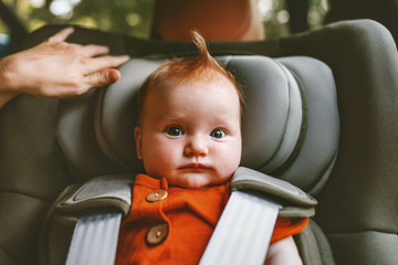 Infant baby sitting in safety car seat child security transportation family lifestyle adorable ginger hair kid portrait