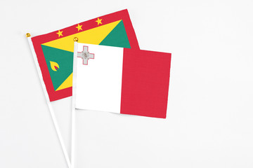 Malta and Grenada stick flags on white background. High quality fabric, miniature national flag. Peaceful global concept.White floor for copy space.