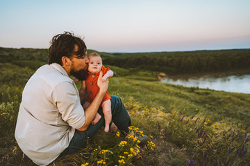 Father kissing baby daughter walking outdoors happy family lifestyle dad and child sitting on grass...