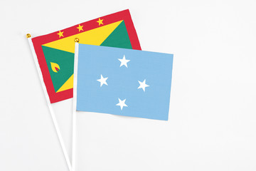 Micronesia and Grenada stick flags on white background. High quality fabric, miniature national flag. Peaceful global concept.White floor for copy space.