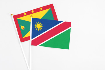 Namibia and Grenada stick flags on white background. High quality fabric, miniature national flag. Peaceful global concept.White floor for copy space.