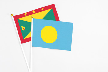 Palau and Grenada stick flags on white background. High quality fabric, miniature national flag. Peaceful global concept.White floor for copy space.