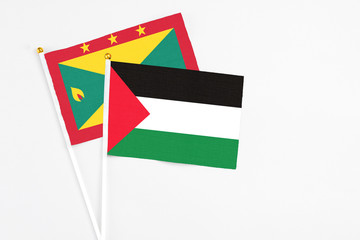 Palestine and Grenada stick flags on white background. High quality fabric, miniature national flag. Peaceful global concept.White floor for copy space.