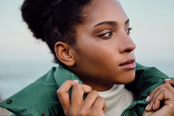 Portrait of beautiful casual African American girl in down jacket thoughtfully looking away outdoor