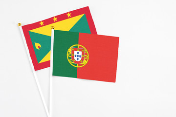 Portugal and Grenada stick flags on white background. High quality fabric, miniature national flag. Peaceful global concept.White floor for copy space.