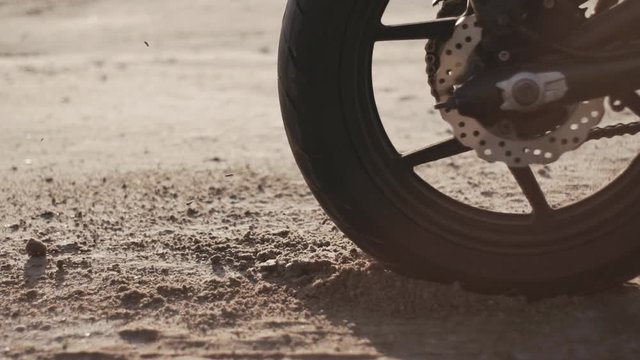 Motorcyclist doing tire burnout in the desert, slow motion. Professional motorcyclist drift and turns on a motorcycle on the ground, a biker does a trick on a motorcycle