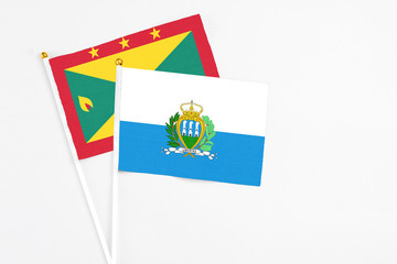 San Marino and Grenada stick flags on white background. High quality fabric, miniature national flag. Peaceful global concept.White floor for copy space.