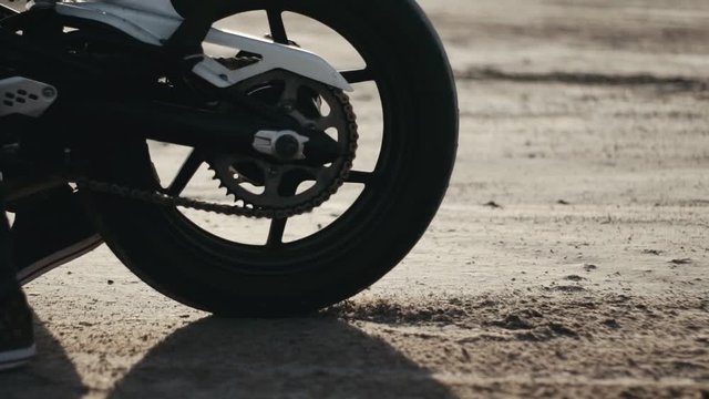Motorcyclist doing tire burnout in the desert, slow motion. Professional motorcyclist drift and turns on a motorcycle on the ground, a biker does a trick on a motorcycle