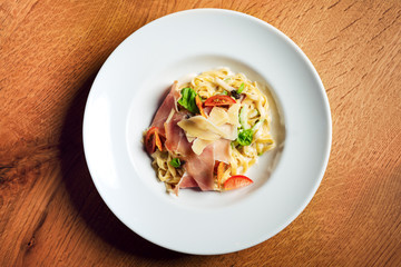Fettuccine Carbonara with parma ham. Served in white plate.