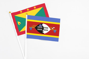Swaziland and Grenada stick flags on white background. High quality fabric, miniature national flag. Peaceful global concept.White floor for copy space.