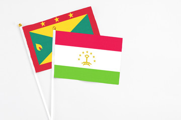 Tajikistan and Grenada stick flags on white background. High quality fabric, miniature national flag. Peaceful global concept.White floor for copy space.